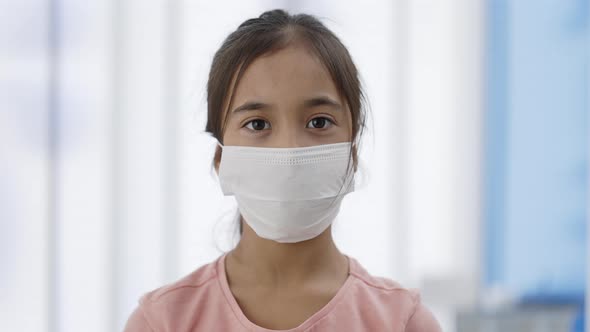 Portrait of Little Girl in Medical Protective Mask Raising Head While Looking to Camera