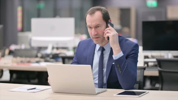 Angry Businessman Talking on Phone in Office
