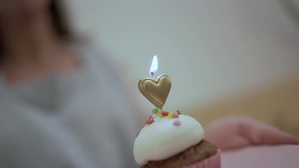 Woman serving birthday cupcake with candle