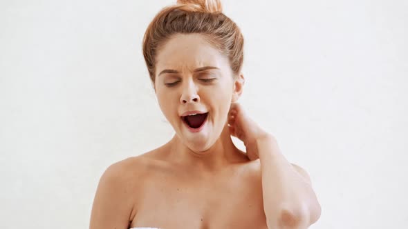 Young Beautiful Naked Girl in Towel Yawning Over White Background