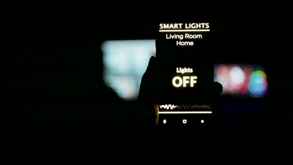 Close Up Shot of Man Holding a Smartphone in Hands with a Smart Light Application