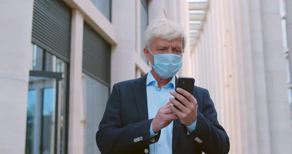 Senior Manager Using Smartphone Outdoor Wearing Safety Mask