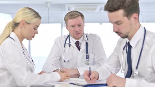 Professional Male Doctor Teaching Team on Paper in Office