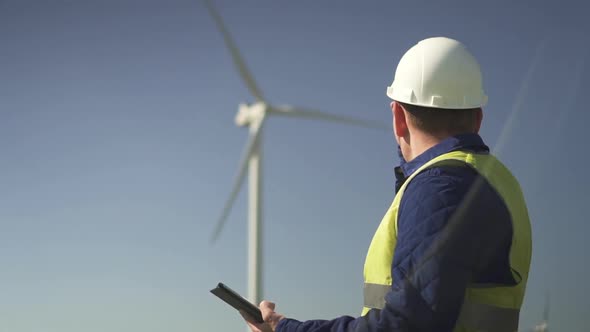 Professional Standing Near Wind Mill and Making Inspections