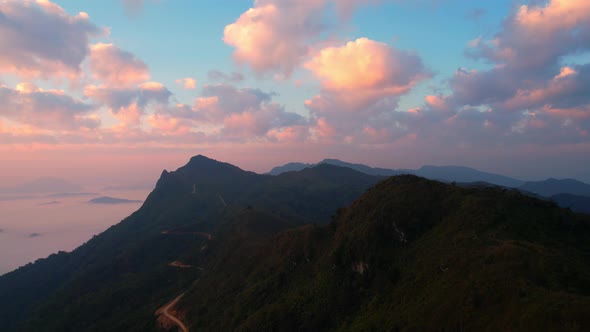 The rays of the sun shine through the clouds into the misty above the mountains in the morning