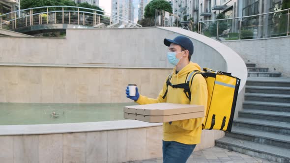 Delivery Man Wearing Thermal Backpack Delivers Pizza Order to a Young Male Customer