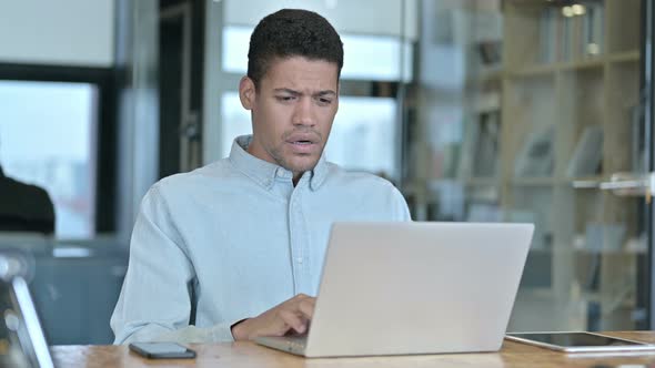 Sad Young African Man Having Loss on Laptop at Work