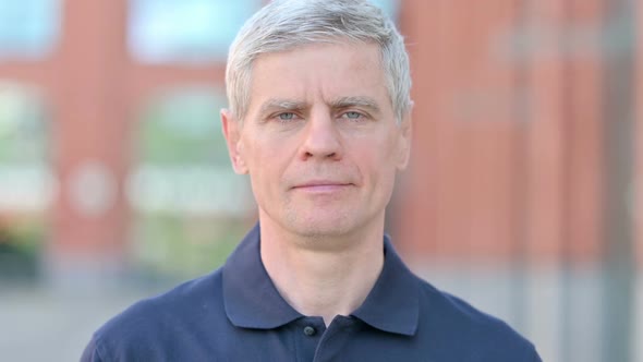 Outdoor Portrait of Serious Middle Aged Man Looking at Camera