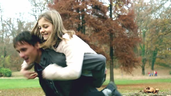 Girl jumps on dad's back in the park