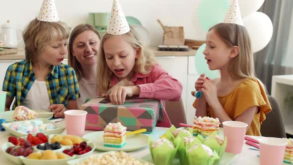 Girl Unwrapping Birthday Gift on Party