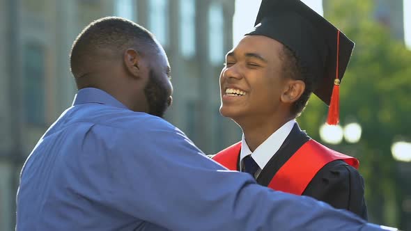 Happy Black Man Hugging Smiling Son in Magisterial Suit, Proud Father, Support