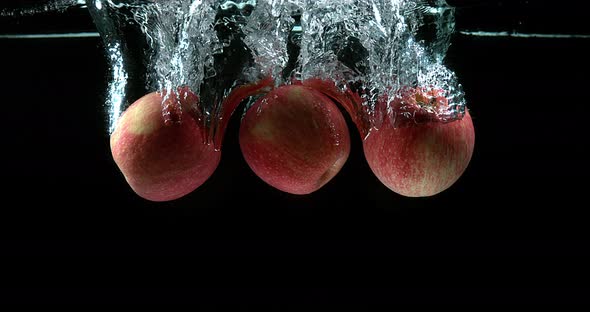 Apples, malus domestica, Fruits entering Water against Black Background, Slow Motion 4K