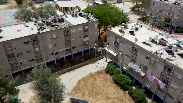 Aerial sliding down drone shot of an empty neighborhood in the city. Buildings surround an empty dir