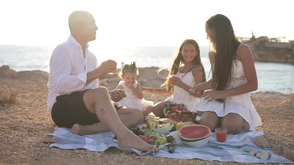 Wide Shot Picnic on Sea Coast in Sunshine of Happy Relaxed Caucasian Family Talking Joking Smiling