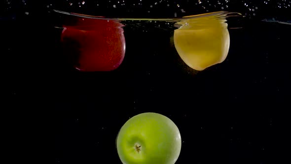 Beautiful green apple being dropped into water in slow motion.