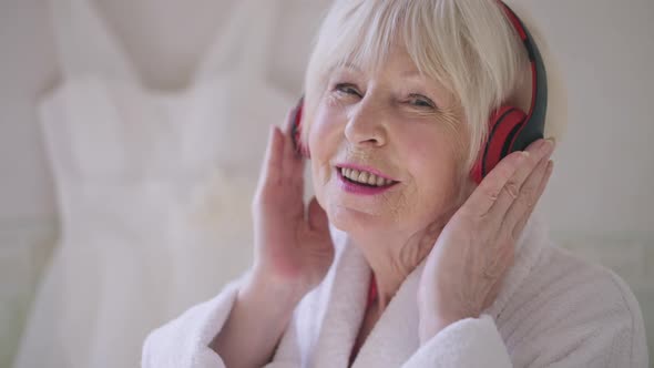 Closeup Face of Joyful Senior Woman with Grey Hair Singing Listening to Music in Headphones Looking