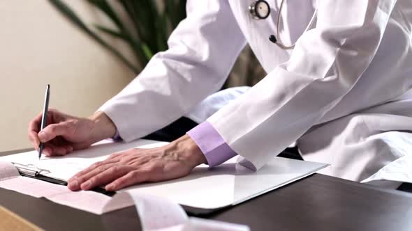 Doctor cardiologist makes records of the result of the analysis of the cardiogram in the hospital.