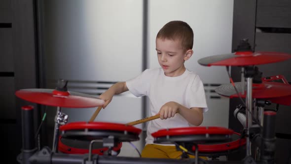 A Boy Plays Electronic Drums at Home, A Little Boy Enjoys Playing the Electronic, Red, Drum at Home