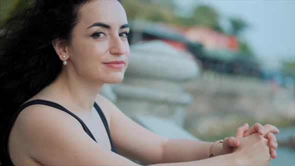 Woman Looking at Ocean View at Sunset. Young Beautiful Girl Enjoying Nature, Looking at the Camera