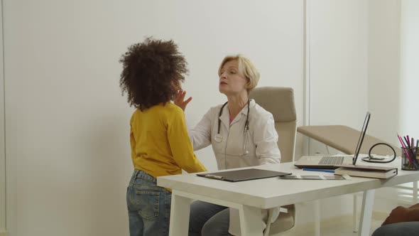 Caring Female Pediatrician Examining Little Multiracial Boy Sore Throat During Medical Checkup