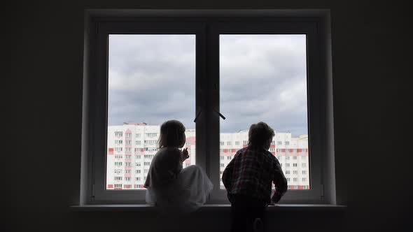 Silhouette of Children on the Background of a Window in the Apartment alt