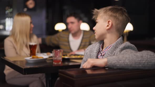 Teenage Boy Looking Back at Mother and Man Gesturing Thumb Down