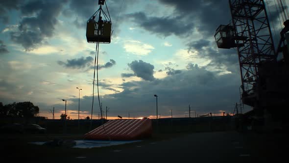 Silhouettes of People Going Down on Crane Platform at Dusk, Construction Site