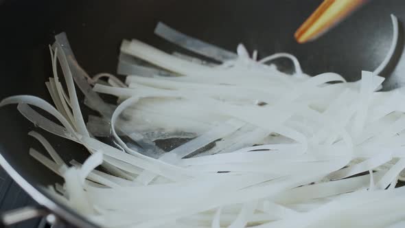 White Asian noodle being cooked and stir fried in the pan