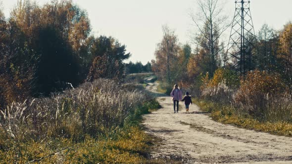 Two of the Sisters' Girls Walk Holding Hands on a Dirt Rural Road an Autumn Day for Outdoor Walks