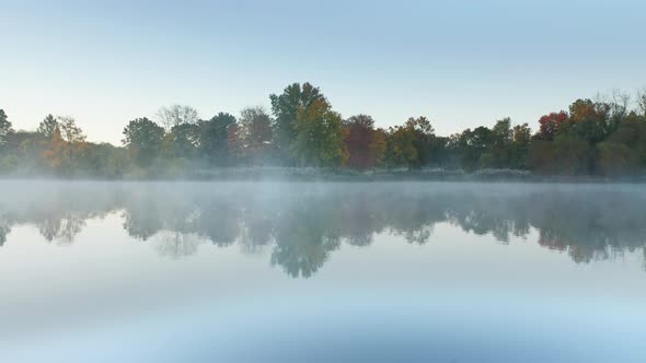 Aerial Morning Fog Above Still Lake Mist and Vibrant Orange Red Forest Trees