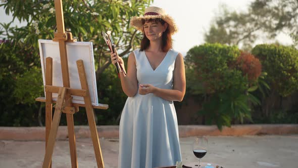 Cheerful Charming Young Woman Holding Painting Tools Sending Air Kiss in Slow Motion Looking at