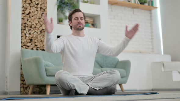 Young Man Meditating on Yoga Mat at Home