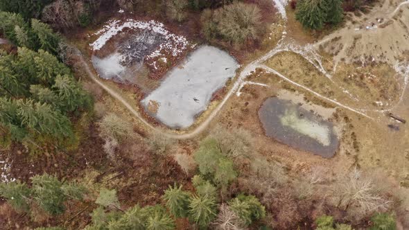 Turning drone shot of frozen lakes in a forest scenery at wintertime with no person landscape view.