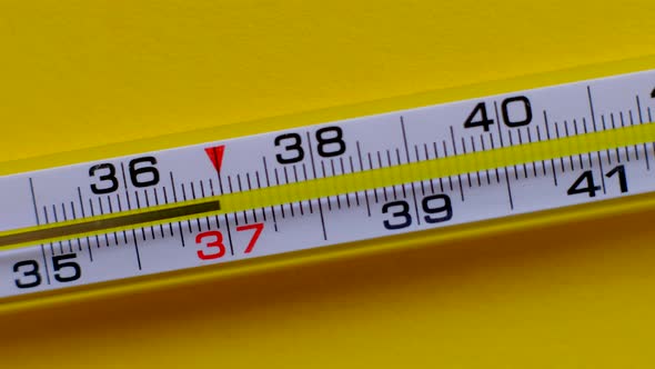 Temperature Rising Shown on a Thermometer on a Yellow Background Closeup