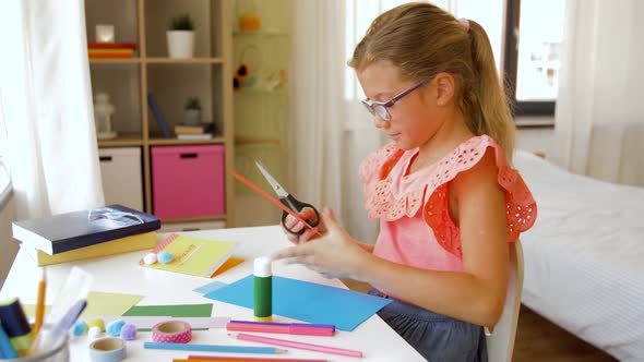 Girl Cutting Color Paper with Scissors at Home