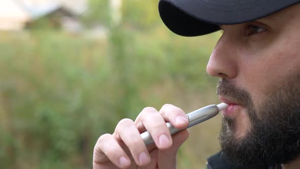 The bearded man smokes an electronic cigarette. close-up