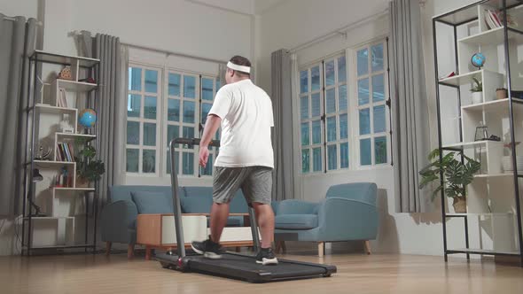 Back View Of Asian Fat Man Training On Walking Treadmill At Home