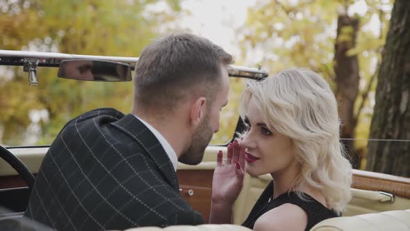 Passionate Blonde with Red Lips Touches Male Beard in Retro Car