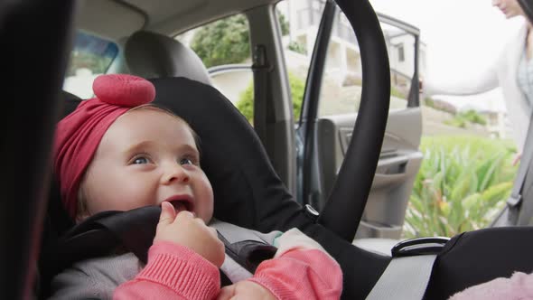 Caucasian mother closing the door after keeping her baby in safety seat in the car