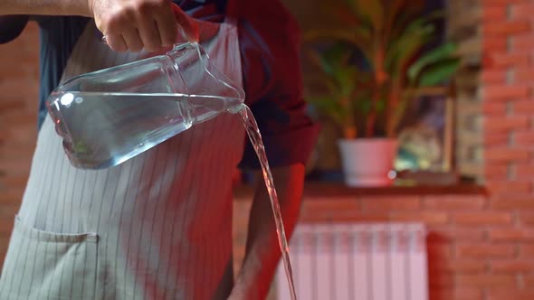 the Man Pours Water From the Glass Carafe