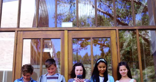 Group of school friends using mobile phone outside school