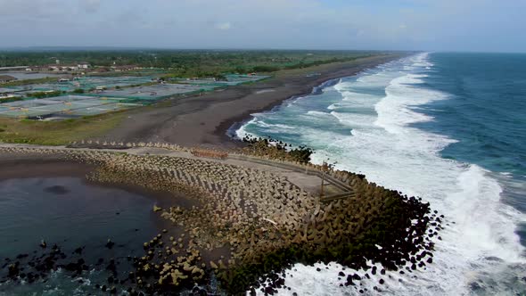 Grand ocean waves hit pier tetrapod breakwater, Glagah Beach, Indonesia, aerial