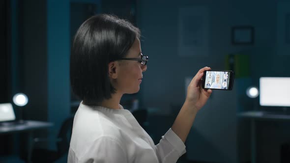 Side View of AfricanAmerican Businesswoman Having Video Conversation on Cellphone Late in Office