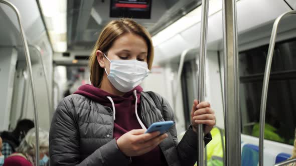 Woman in Protective Mask Using Smartphone Standing in Underground Carriage