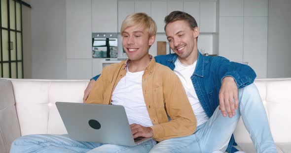 Two Male Gay Couple Using Laptop Computer for Video Calling Talking Distantly with Friends