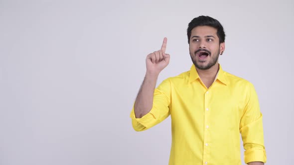 Young Happy Bearded Indian Businessman Thinking While Pointing Up