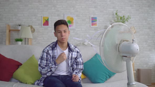 Young Asian Man Saved From the Heat Sitting in Front of a Working Fan the Concept of Heat