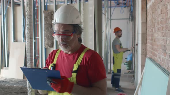 Mature Foreman Inspecting Unfinished Construction Site