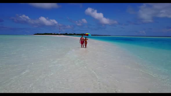 Two people sunbathe on luxury shore beach holiday by turquoise ocean with white sandy background of 