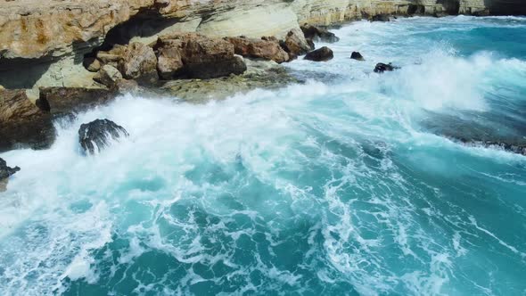 Aerial View of Waves Break on Rocks in a Blue Ocean Sea Waves on Beautiful Beach Bird's Eye View of